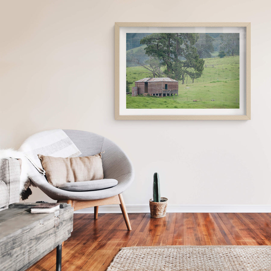 Bemboka Woolshed at The Woolshed, a weatherboard woolshed sits on low timber stumps against a slope of green pasture.