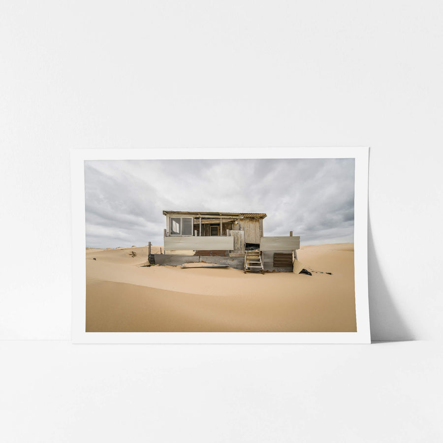 Eleven at Tin City, clean lines in a sandy foreground before a weathered Tin City shack.