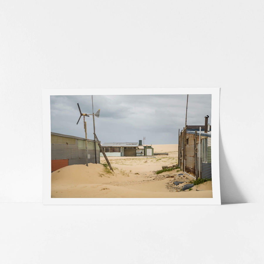 Facing South at Tin City, sand drifts between corrugated iron shacks, banking up against walls and burying the base.