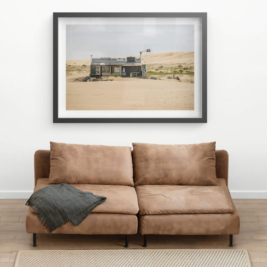 Filthy Phills Ranch at Tin City, sand drifts against the base of a low shack built from corrugated iron, timber cladding.