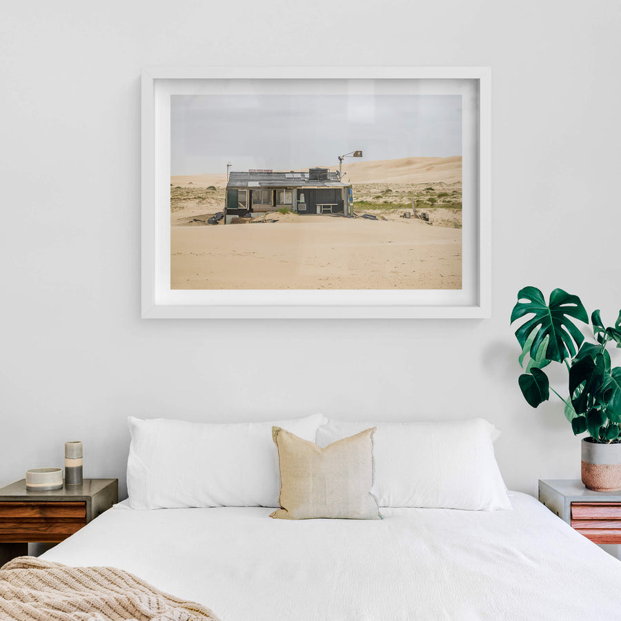 Filthy Phills Ranch at Tin City, sand drifts against the base of a low shack built from corrugated iron, timber cladding.