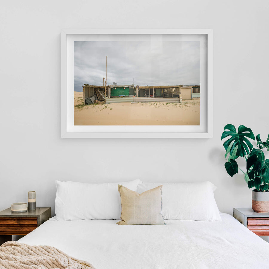 Nine at Tin City, corrugated iron and shade cloth hold together a low sprawl of shack against the dunes.