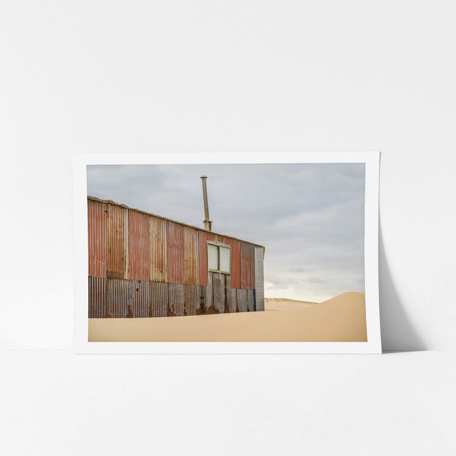 Red Walls at Tin City, corrugated iron panels in rust red, faded salmon, grey and bare steel form the wall of a shack.