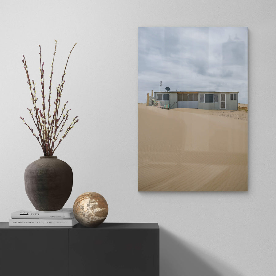 Ripples at Tin City, sand rises in a smooth, wind-rippled drift against a low corrugated iron shack.