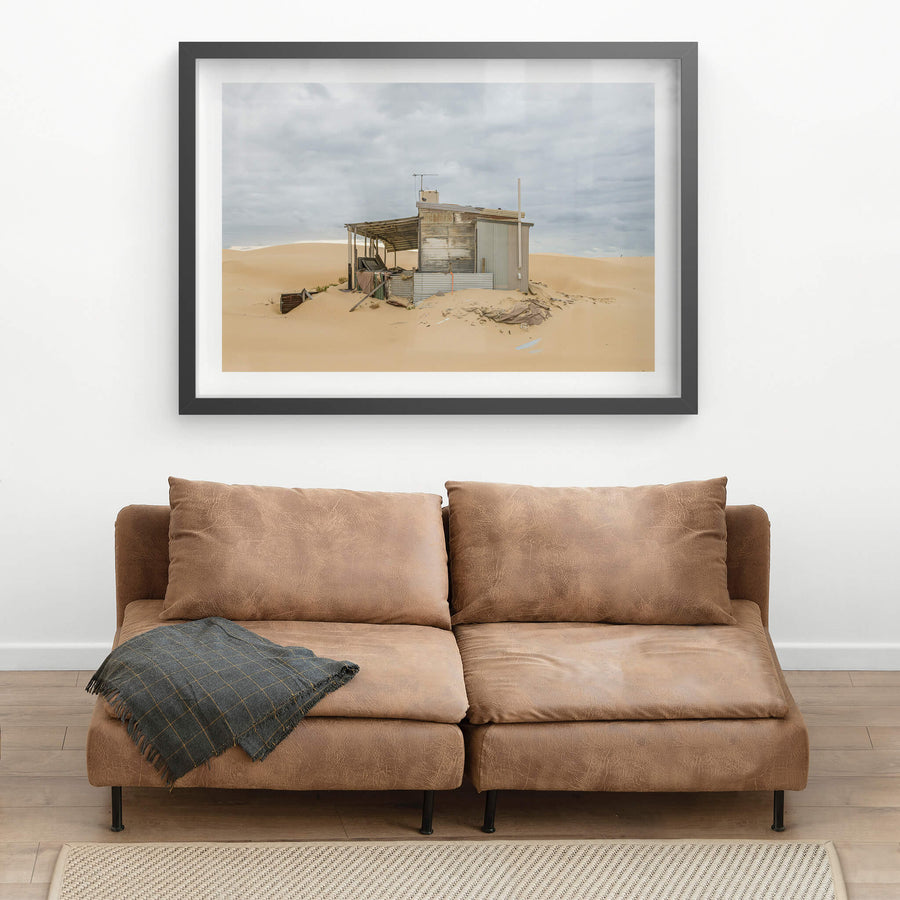 The Porch at Tin City, a corrugated iron shack sits half-swallowed by sand.