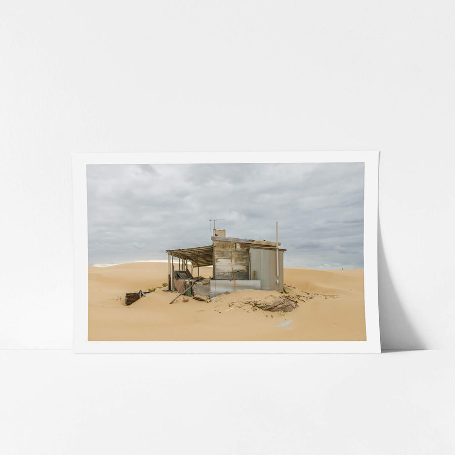 The Porch at Tin City, a corrugated iron shack sits half-swallowed by sand.