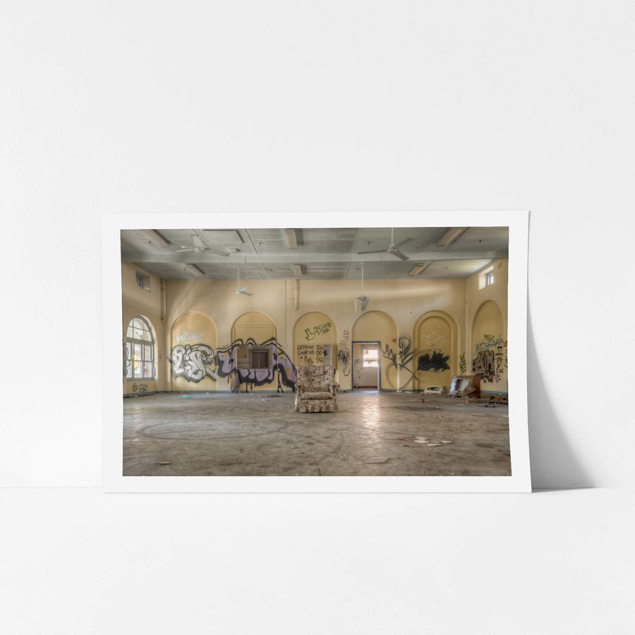 Lone Chair at Waterfall Sanatorium, a floral armchair sits alone at the centre of a large hall.