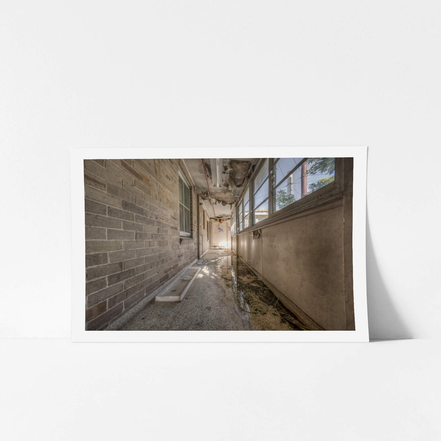 Side Hall at Waterfall Sanatorium, a narrow enclosed corridor runs between a brick wall and a bank of steel-framed windows.