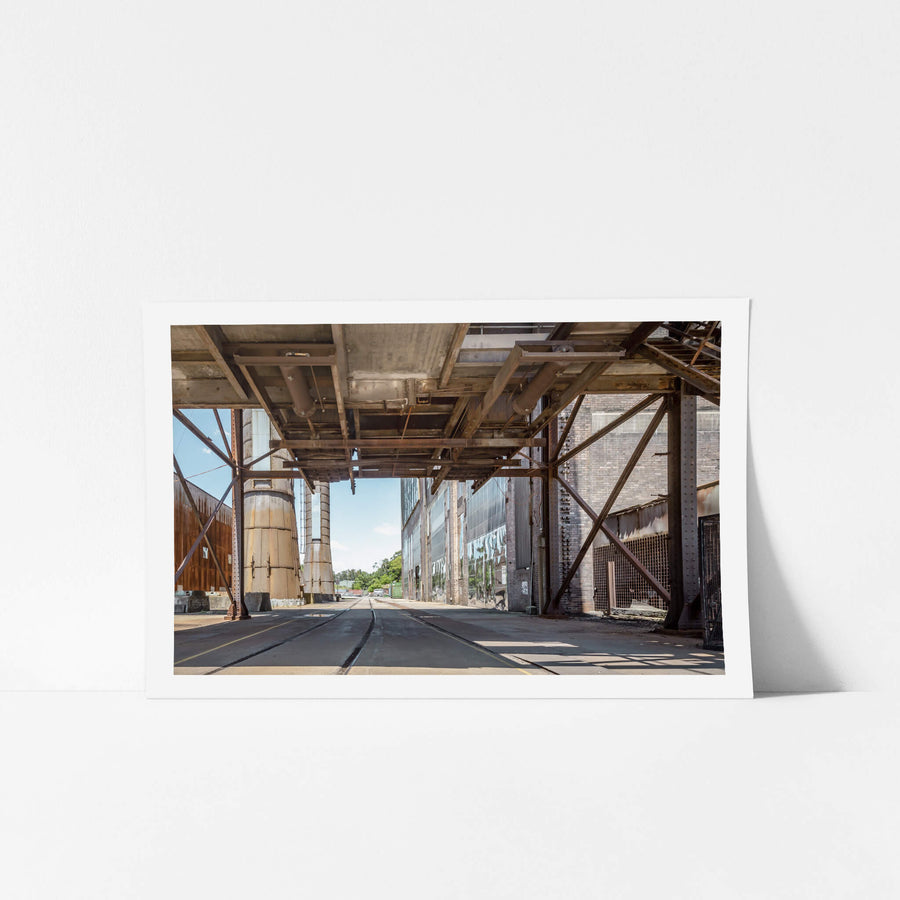 Railway Corridor at White Bay Power Station, rail lines run flush with the concrete floor beneath a heavy steel gantry.