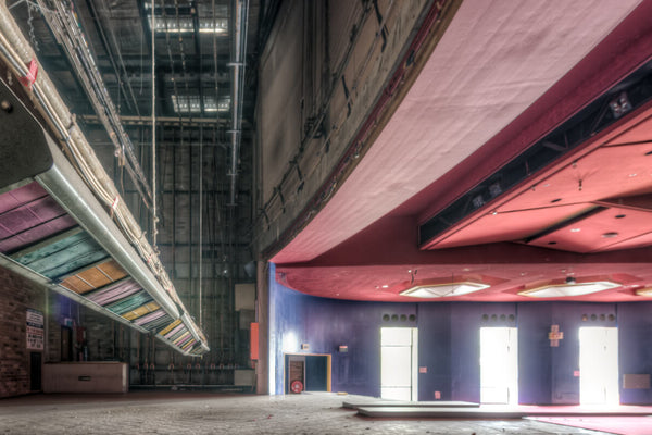 Interior of the abandoned Bankstown RSL auditorium, showcasing its vibrant red ceiling, colorful stage rigging, and empty performance space before demolition. Captured by Lost Collective.