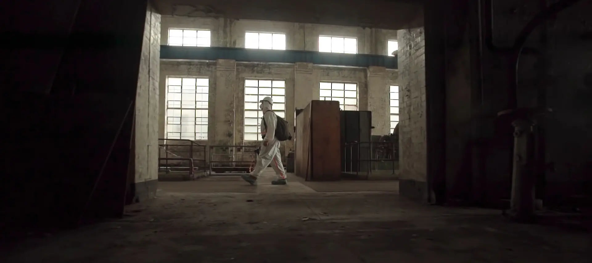 Brett Patman exploring the abandoned White Bay Power Station, wearing protective gear inside the decayed industrial space with large windows in the background.