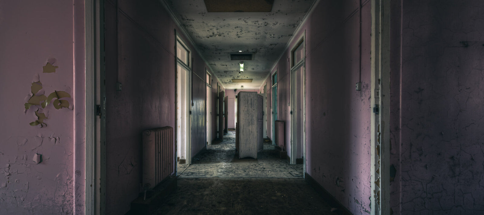 A decaying hospital hallway with peeling paint, dim lighting, and abandoned furniture, capturing the eerie and haunting atmosphere of the space.