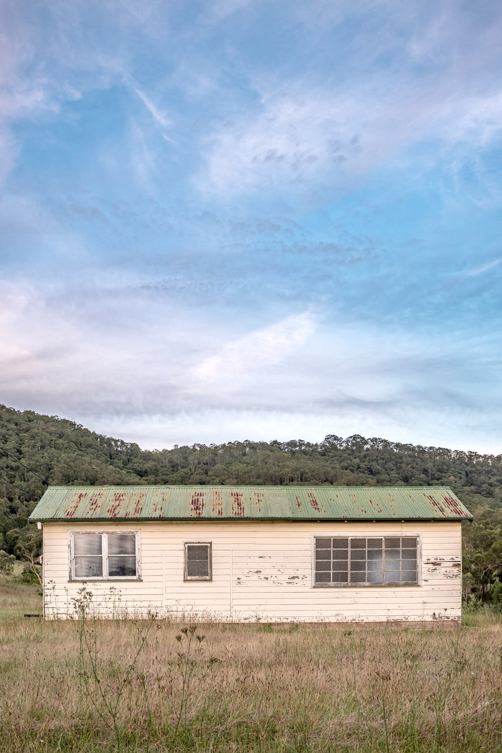 Hunter Shack at A Place to Call Home, a single-storey weatherboard building sits low in a clearing of dry grass and thistles.