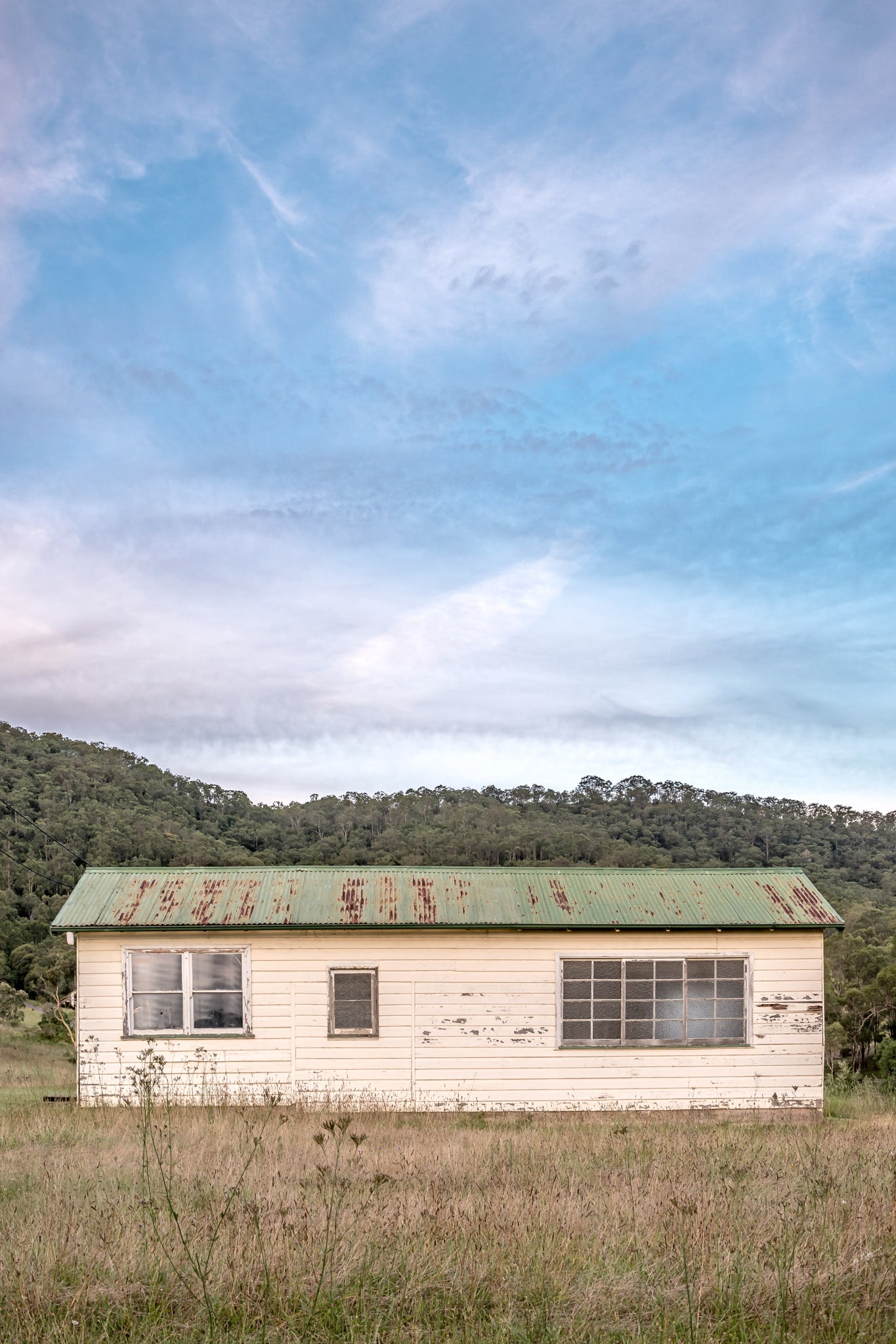 Hunter Shack at A Place to Call Home, a single-storey weatherboard building sits low in a clearing of dry grass and thistles.