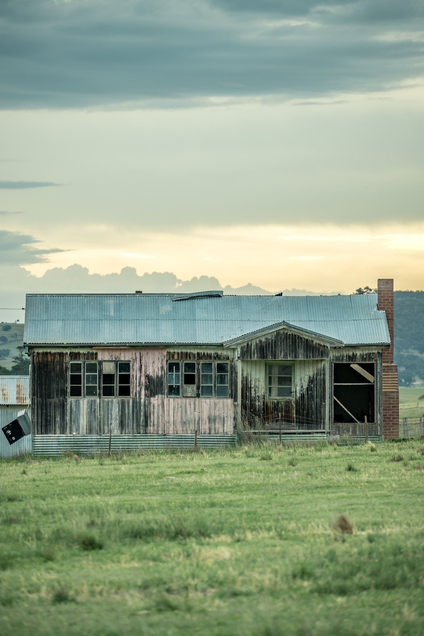 Matong Hut at A Place to Call Home, a weatherboard farmhouse sits low in open green paddock.