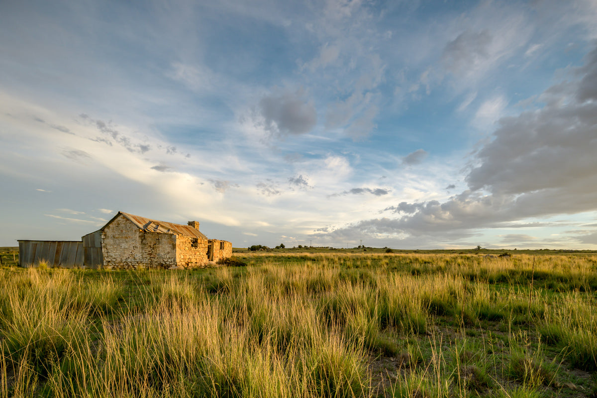 Stone Drover's Hut at A Place to Call Home, a stone cottage sits low against open grassland, its rough-cut walls catching late afternoon light.