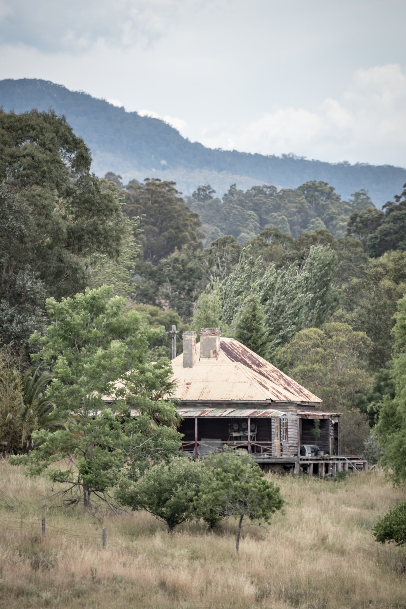Wyndam Home at A Place to Call Home, a weatherboard homestead sits low in dry grass, its hipped roof a patchwork of rust.