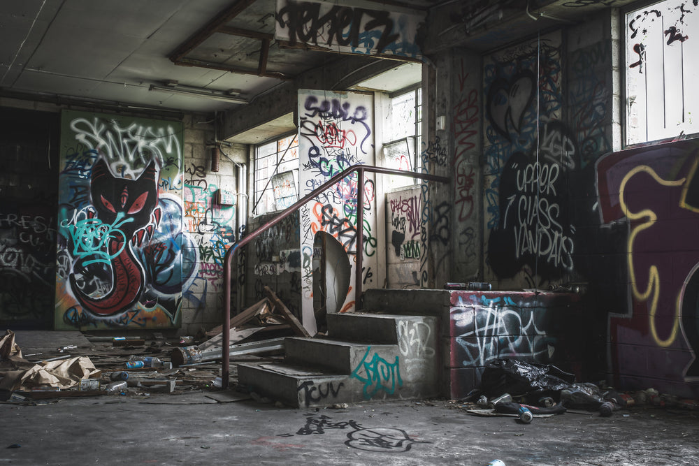 Basement Exit at Abandoned Bakery, concrete steps rise from a debris-covered basement floor toward a narrow doorway.