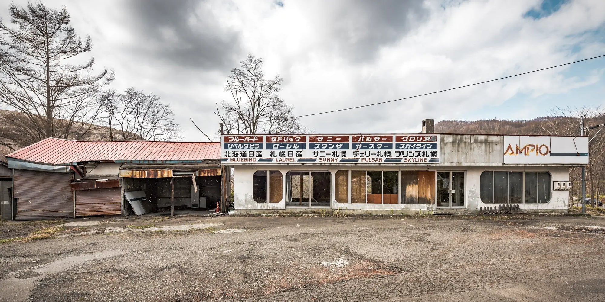 Abandoned car dealership in Hokkaido, Japan, with weathered signage and overgrown surroundings. A haunting yet beautiful representation of urban decay.