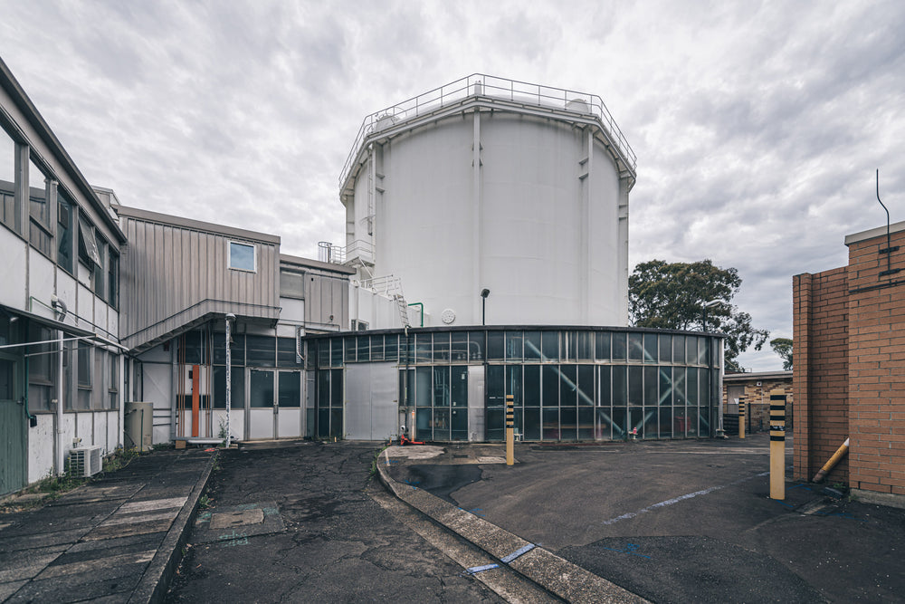 Containment Building and Auxiallry Buildings at ANSTO HIFAR, a large white cylindrical containment building rises.