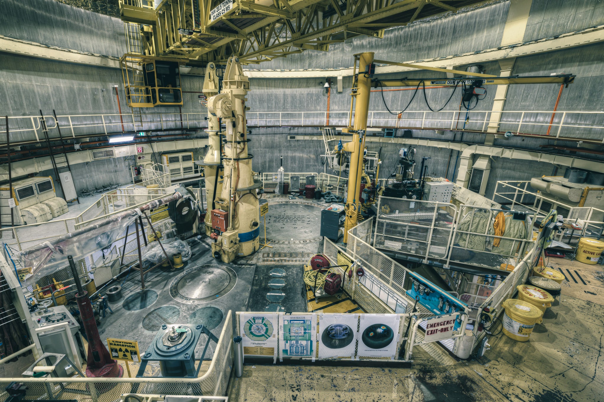 Top Plate Beneath Polar Crane at ANSTO HIFAR, yellow lab coats hang on the mesh walls of the right walkway, worn.