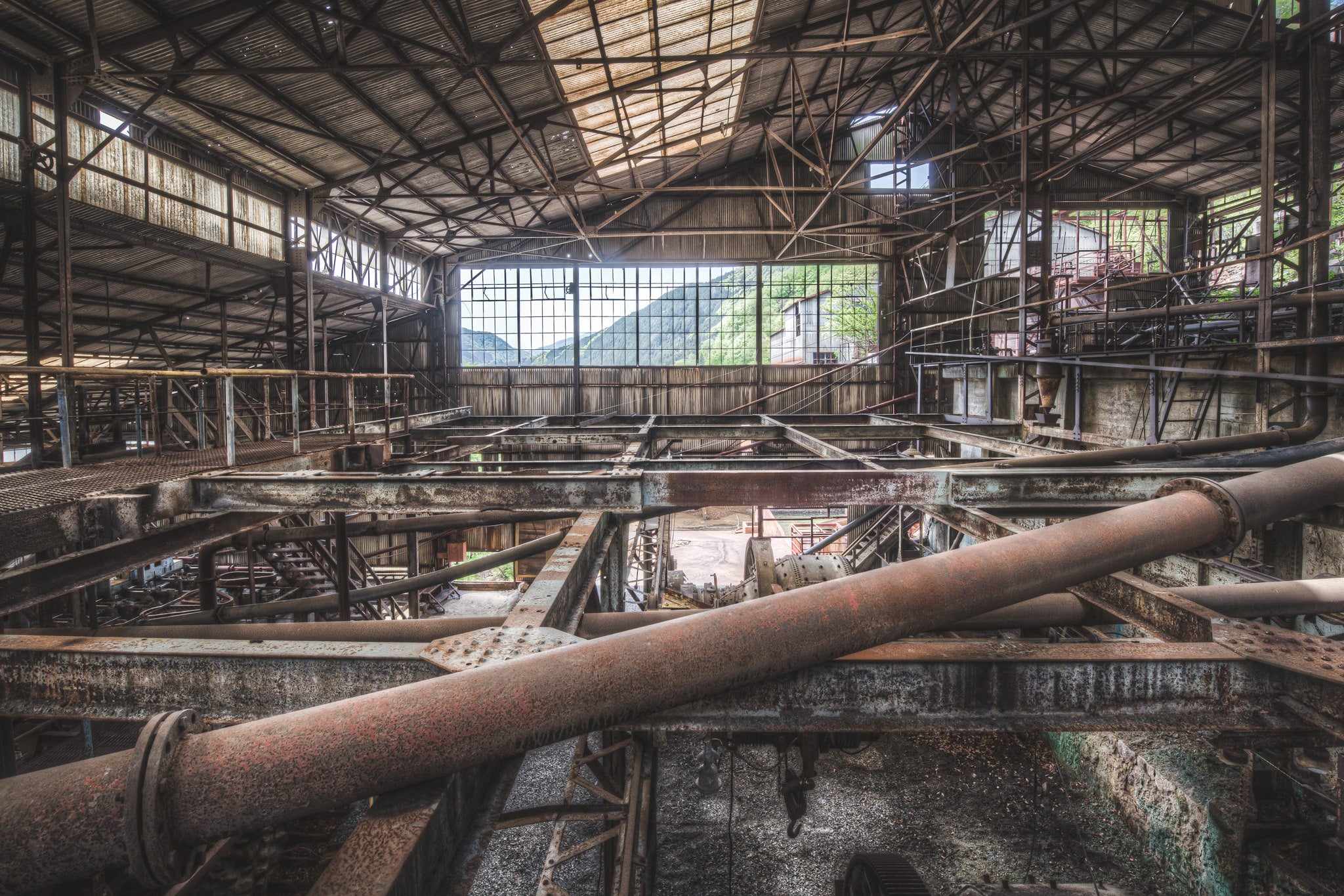Mountain View at Ashio Copper Mine, steel trusses and heavy pipework fill the interior of a vast processing shed.