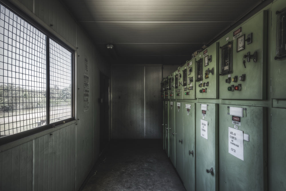 Pale green electrical control panels with red and green indicator lights and a set of keys still hanging from a hook, in the breaker room at Awaba Colliery.