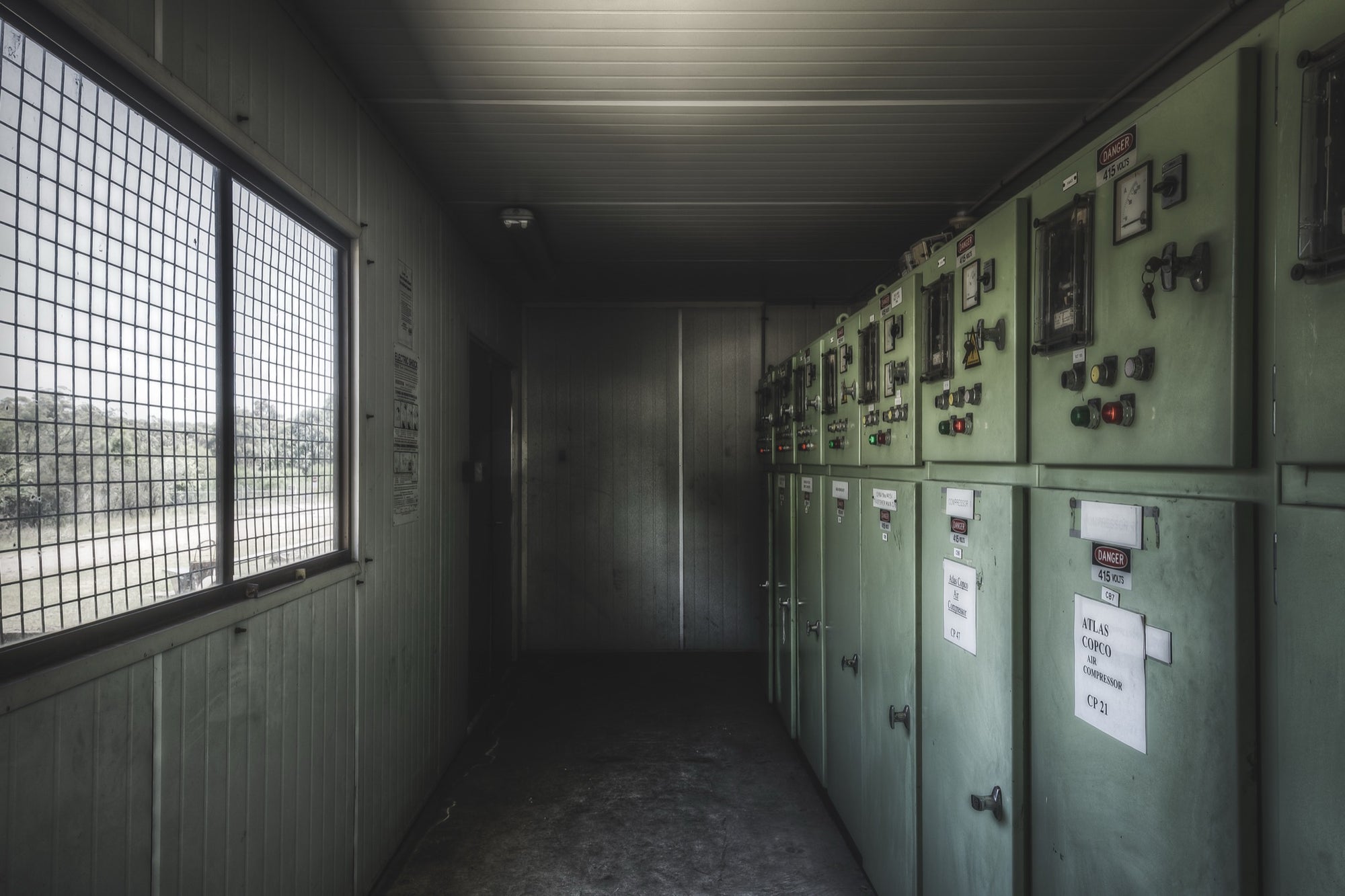 Pale green electrical control panels with red and green indicator lights and a set of keys still hanging from a hook, in the breaker room at Awaba Colliery.