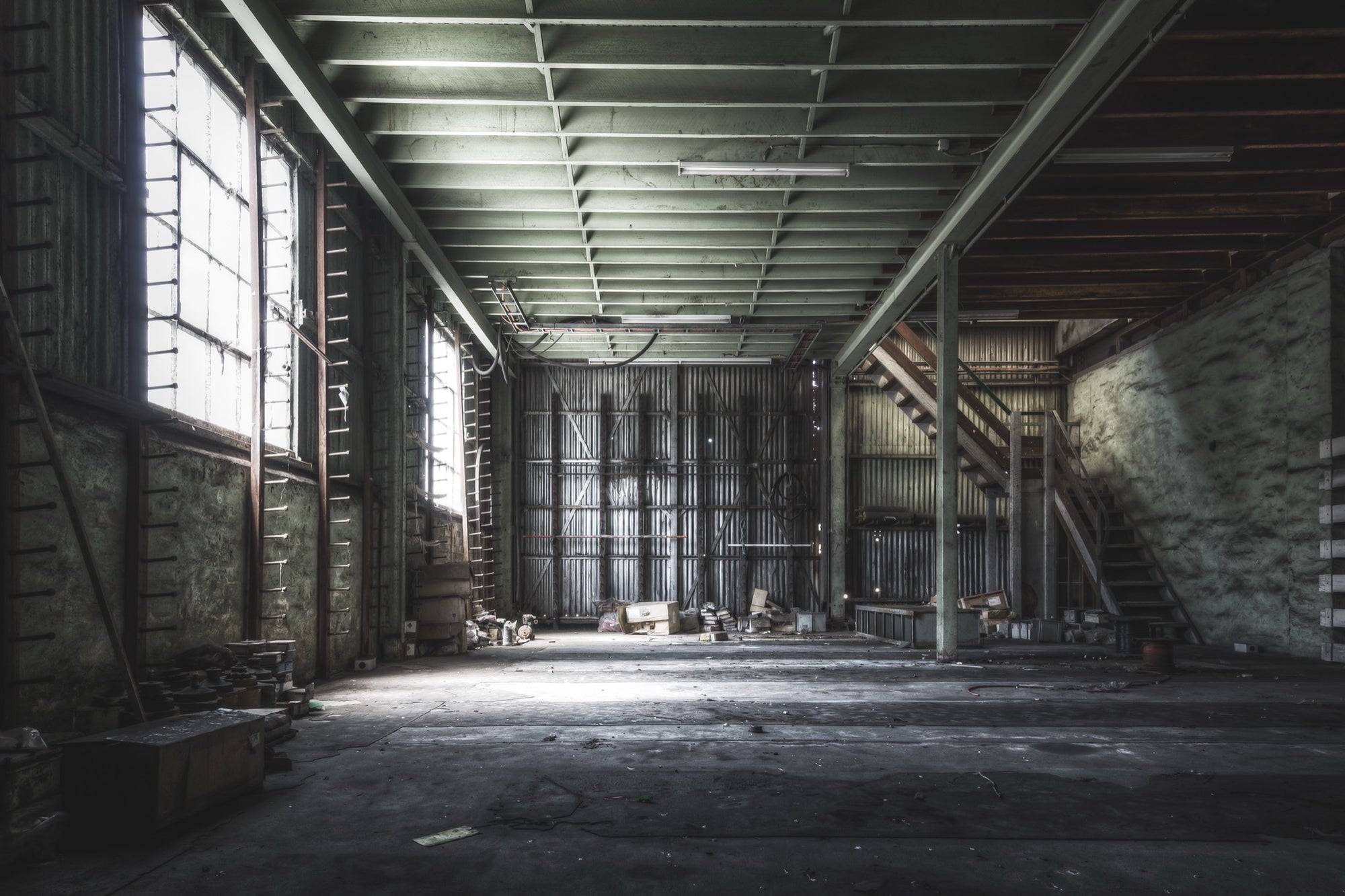 Steel storage racks, sprocket drives on the floor, and what appear to be PLC units near a timber staircase inside the stores building at Awaba Colliery, photographed in 2015.