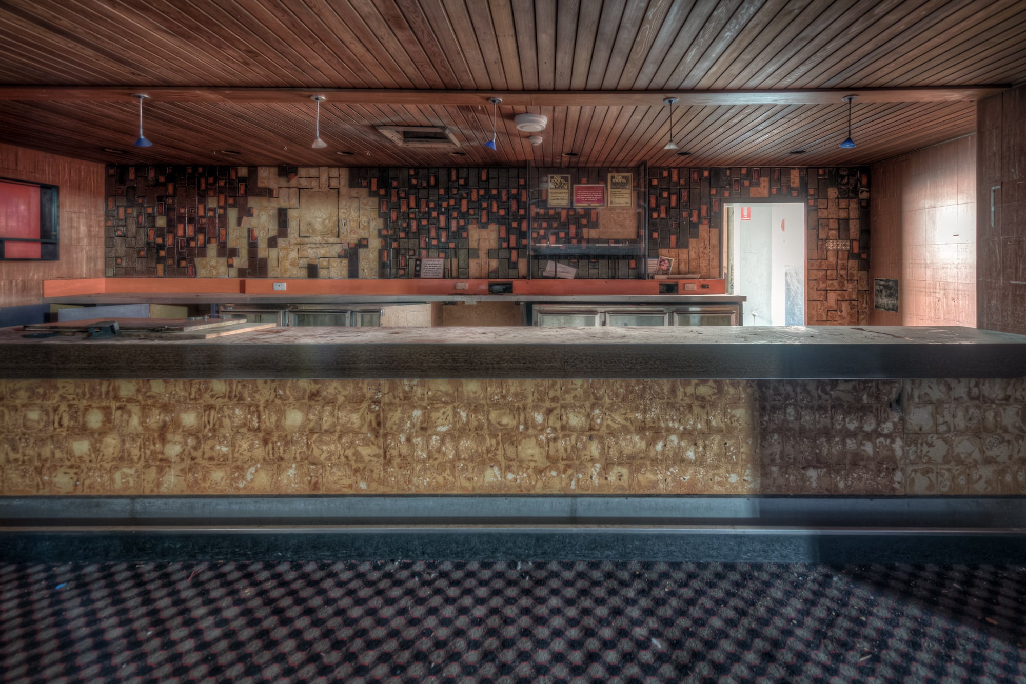 Nightclub Bar at Bankstown RSL, a long bar counter runs the width of the room, its stone-clad face pitted and uneven.