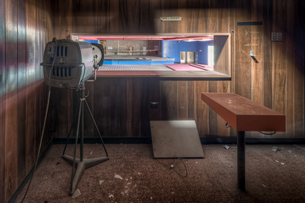 Spotlights at Bankstown RSL, a stage spotlight on a tripod stands in a small backstage room lined with dark timber veneer.