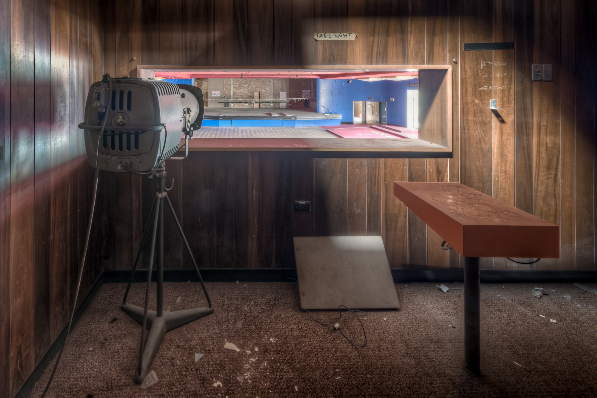 Spotlights at Bankstown RSL, a stage spotlight on a tripod stands in a small backstage room lined with dark timber veneer.