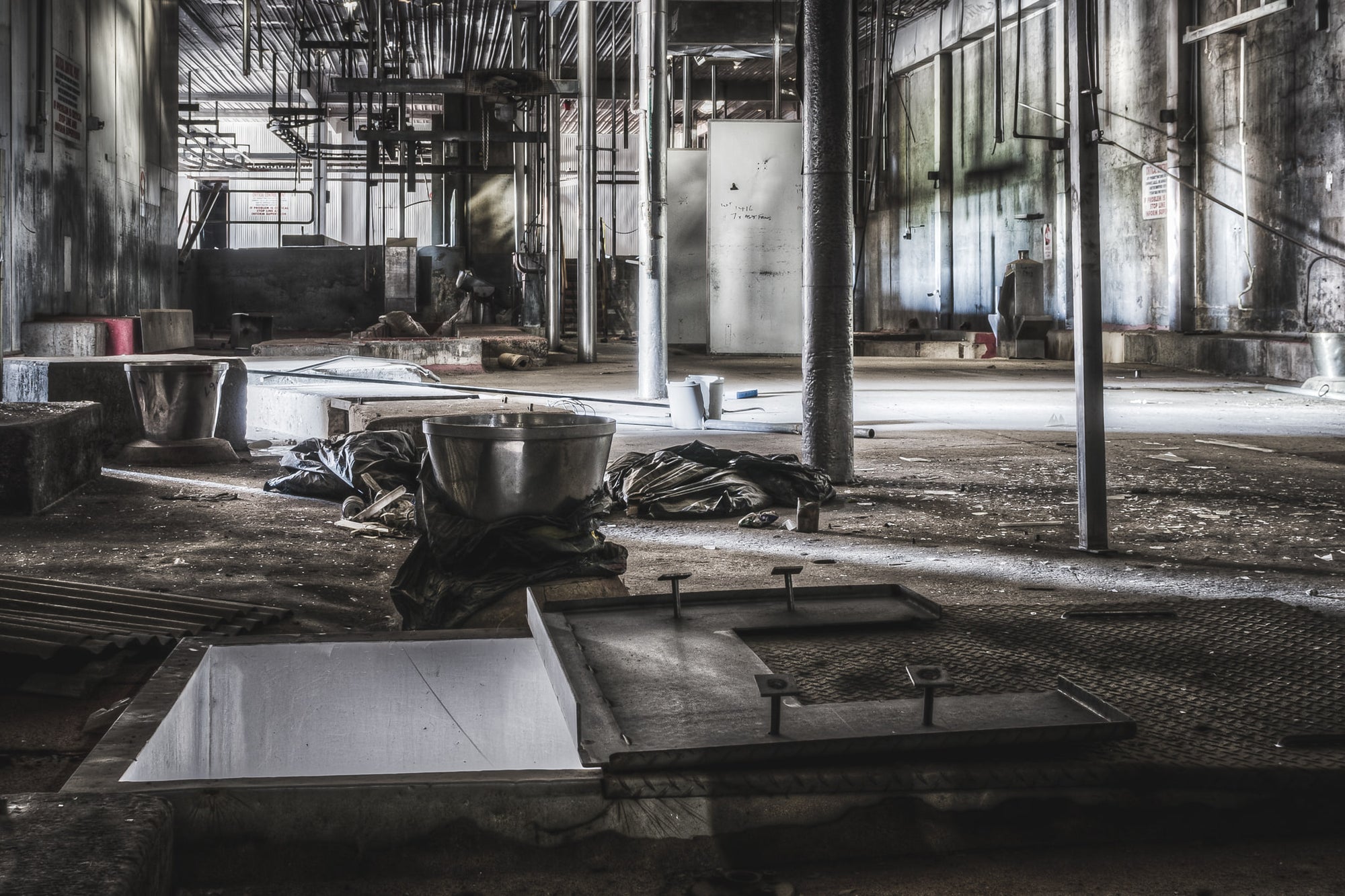 Hide Puller at Blayney Abattoir, a stainless steel bowl sits on crumpled tarpaulin beside an open floor chute.