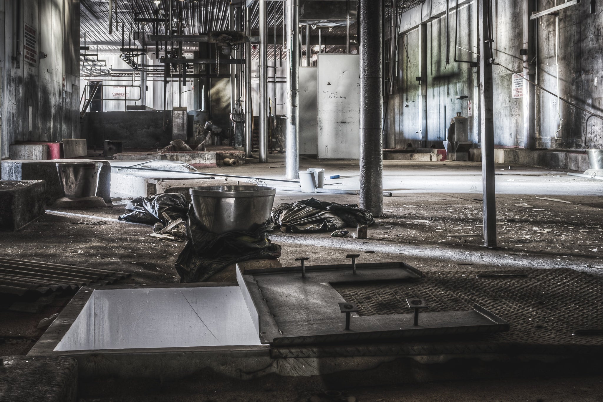 Hide Puller at Blayney Abattoir, a stainless steel bowl sits on crumpled tarpaulin beside an open floor chute.