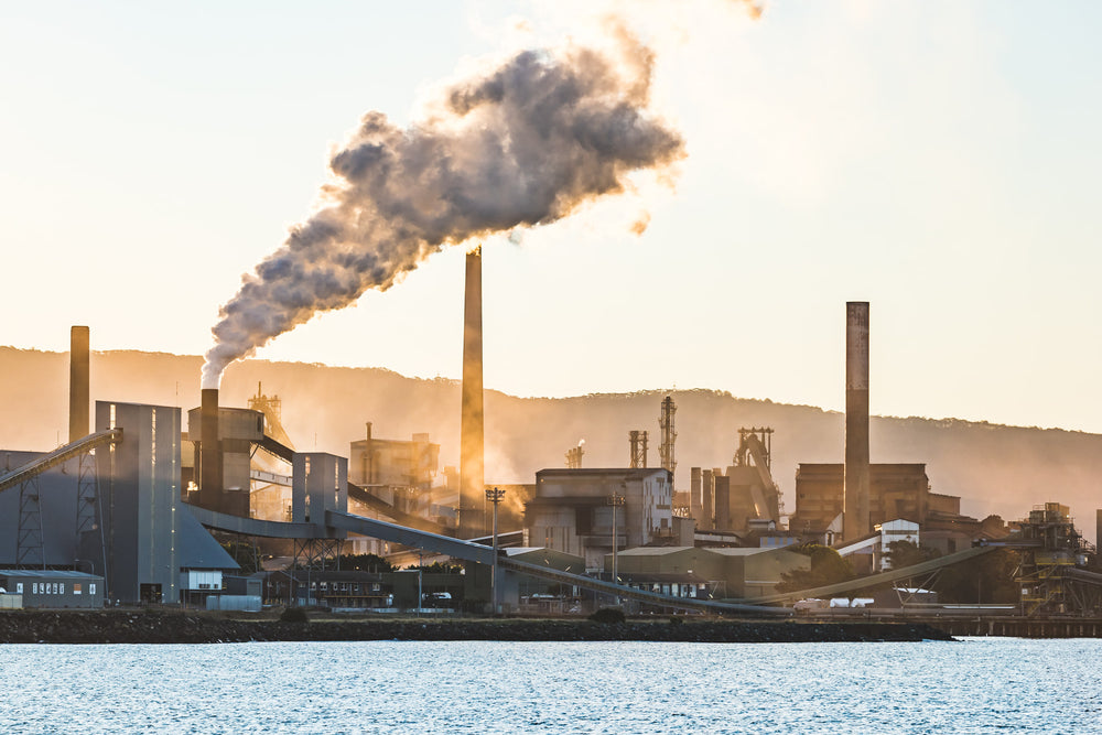 Port Kembla Sunset at BlueScope Port Kembla, smoke pours from a tall stack and drifts south across the steelworks skyline.