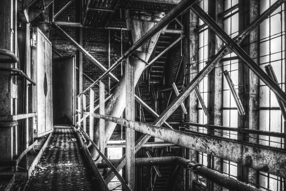 Boiler House Walkway at Bradmill Denim, steel cross-bracing and diagonal pipes cut across a narrow elevated walkway inside.