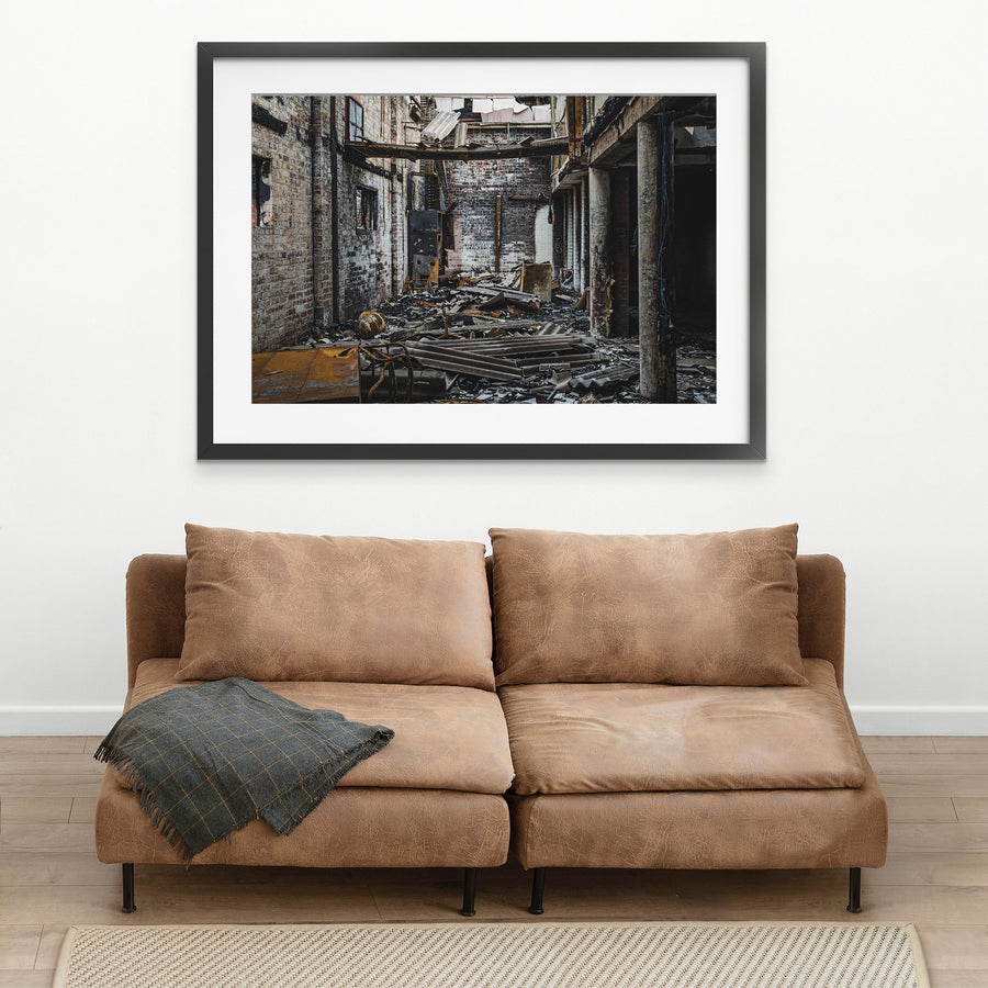 Gutted brick interior of a fire-damaged manufacturing building at the former Bradmill factory in Yarraville, with charred debris on the floor, soot-stained walls and exposed steel framing overhead.
