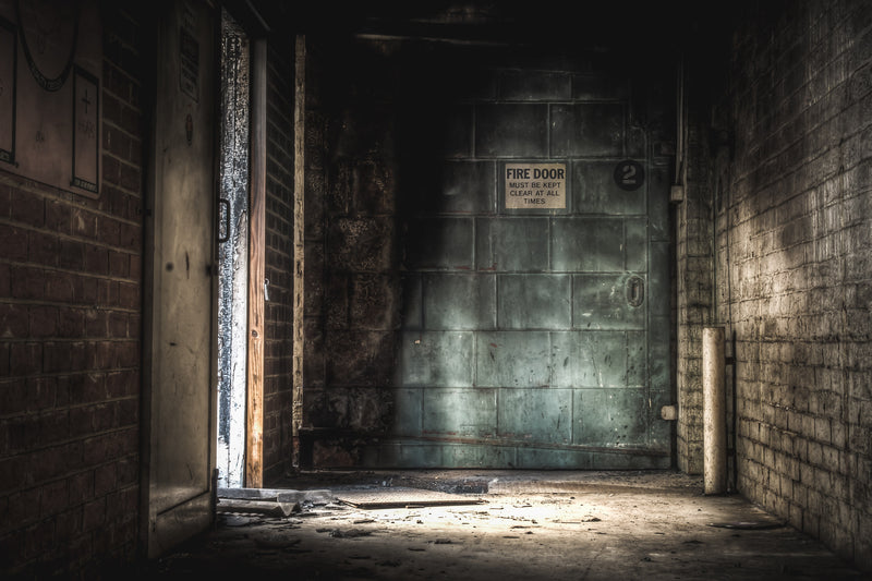 Doorway at Bradmill Denim, a heavy steel fire door marked "2" fills the end of a narrow brick corridor.