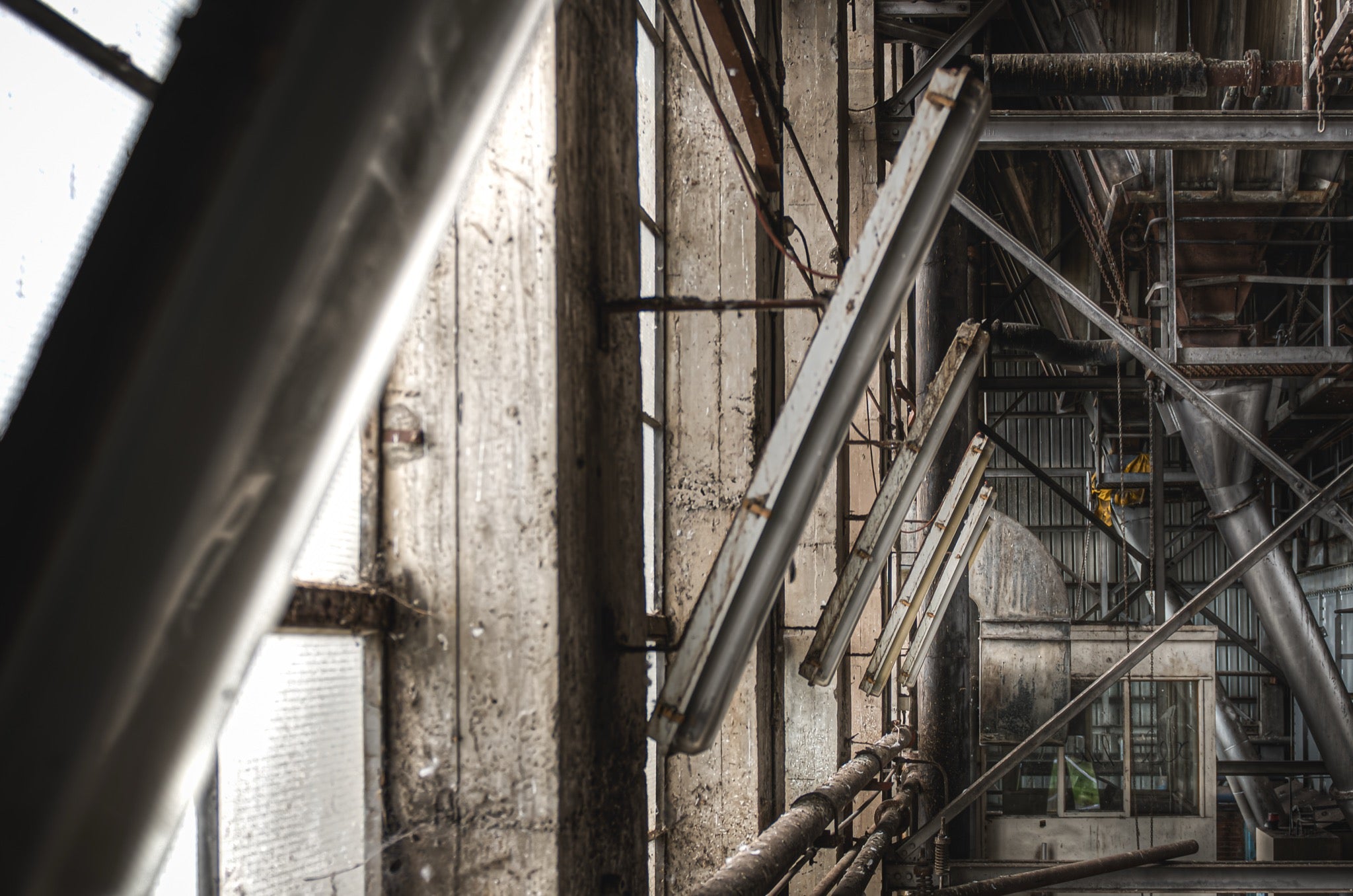 Multi-level industrial interior at the former Bradmill factory in Yarraville, showing concrete columns, large windows, steel beams, overhead ducting and angled fluorescent tube fittings.