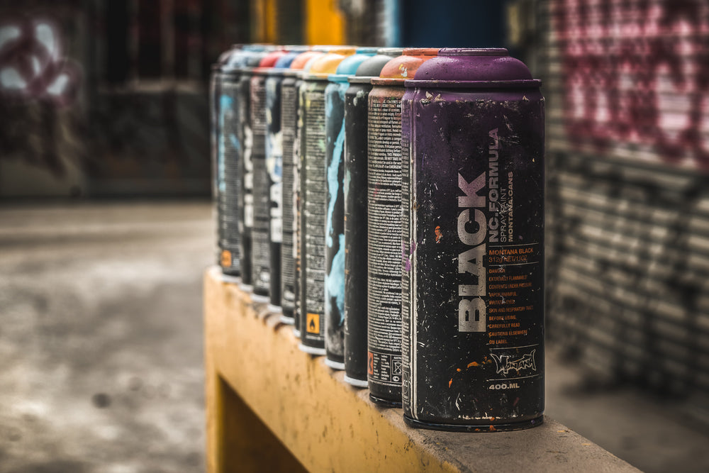Paint at Bradmill Denim, montana Black 400ml cans lined up on a concrete ledge, labels spattered and worn.