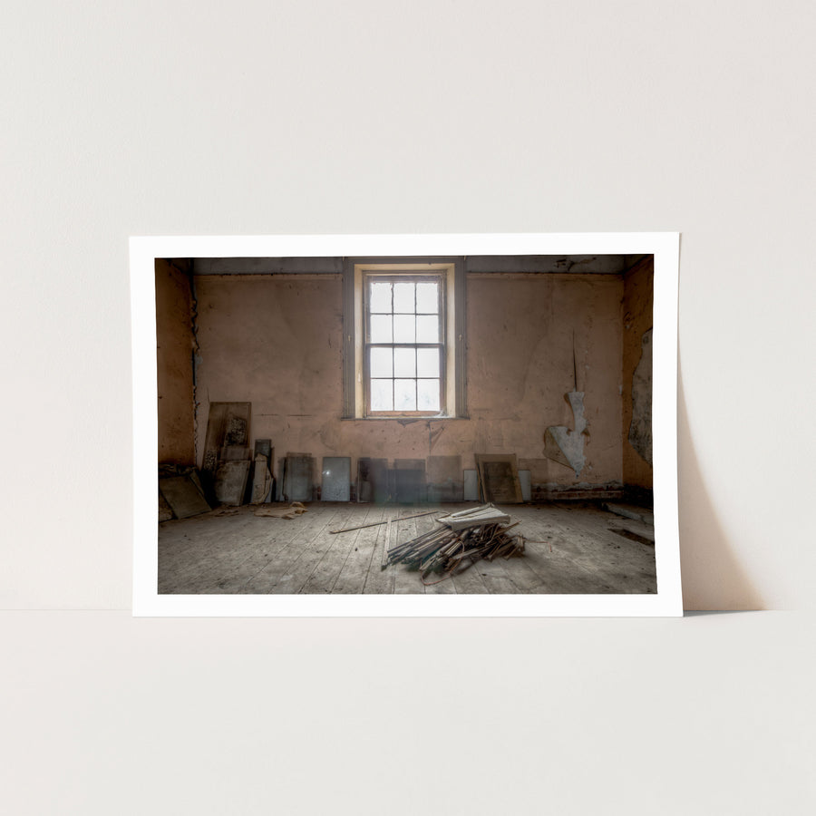A tall multi-pane sash window in an upper room under restoration at the Braidwood Hotel, with peeling pink plaster walls and bare timber boards leaned against them.