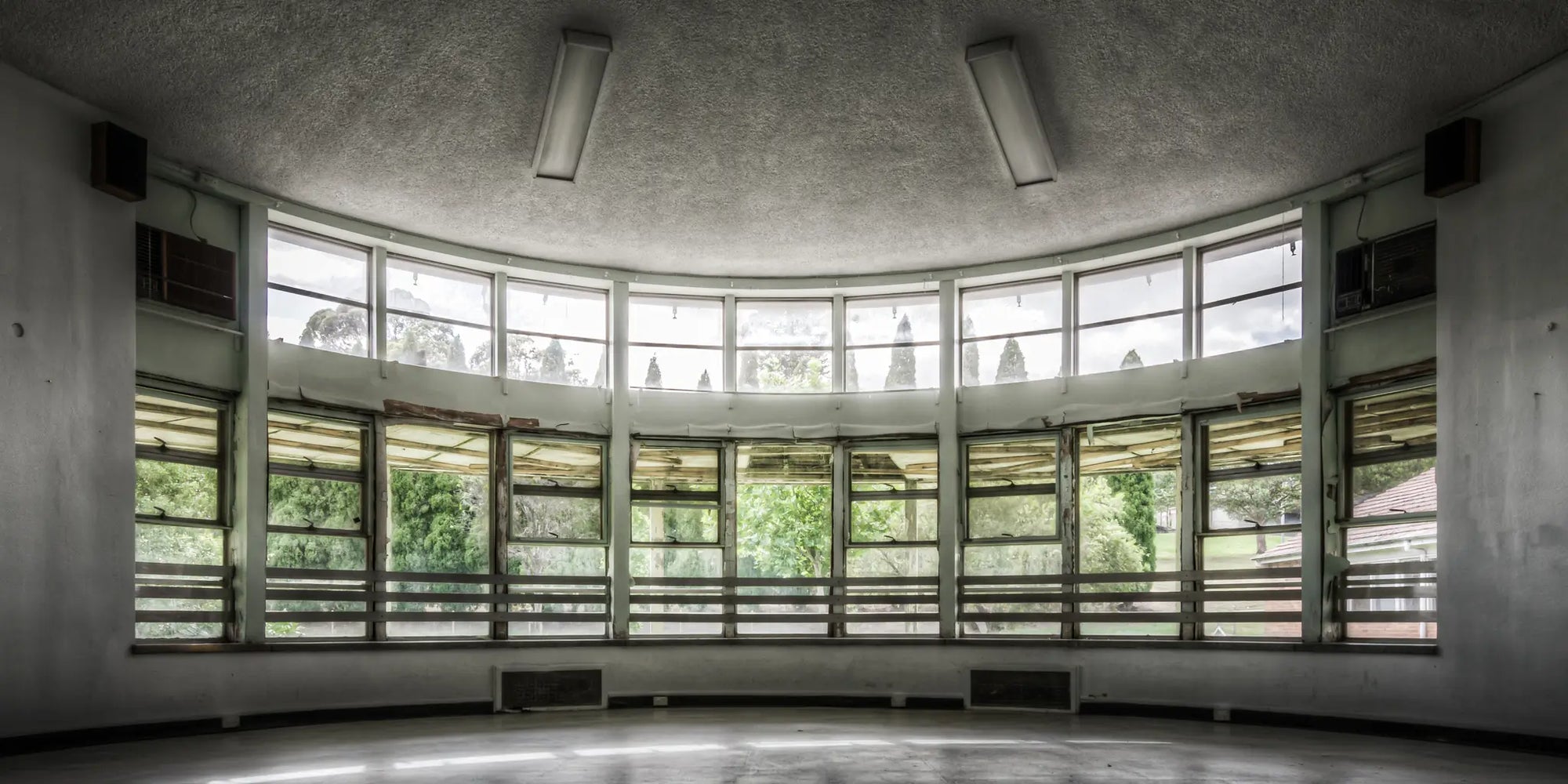 Panoramic view of the curved entertainment room at Callan Park, featuring large windows overlooking lush greenery. A historic space that embodies timeless architectural charm.