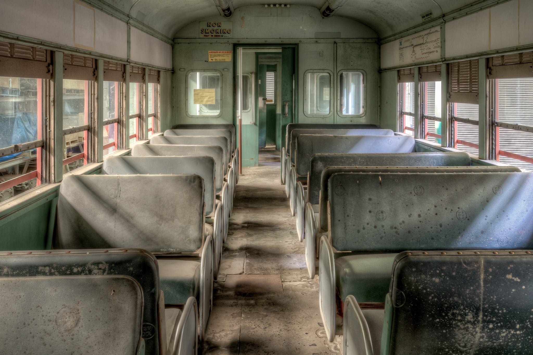 4052 Interior Close at Eveleigh Paint Shop, two rows of moulded metal seats line the aisle of Car 4052, their green paint dulled under a thick film of dust and mottled with age spots.