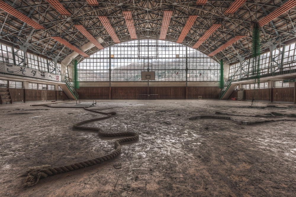 Gymnasium at Family School Fureai, a thick climbing rope lies coiled across the gymnasium floor like something shed.
