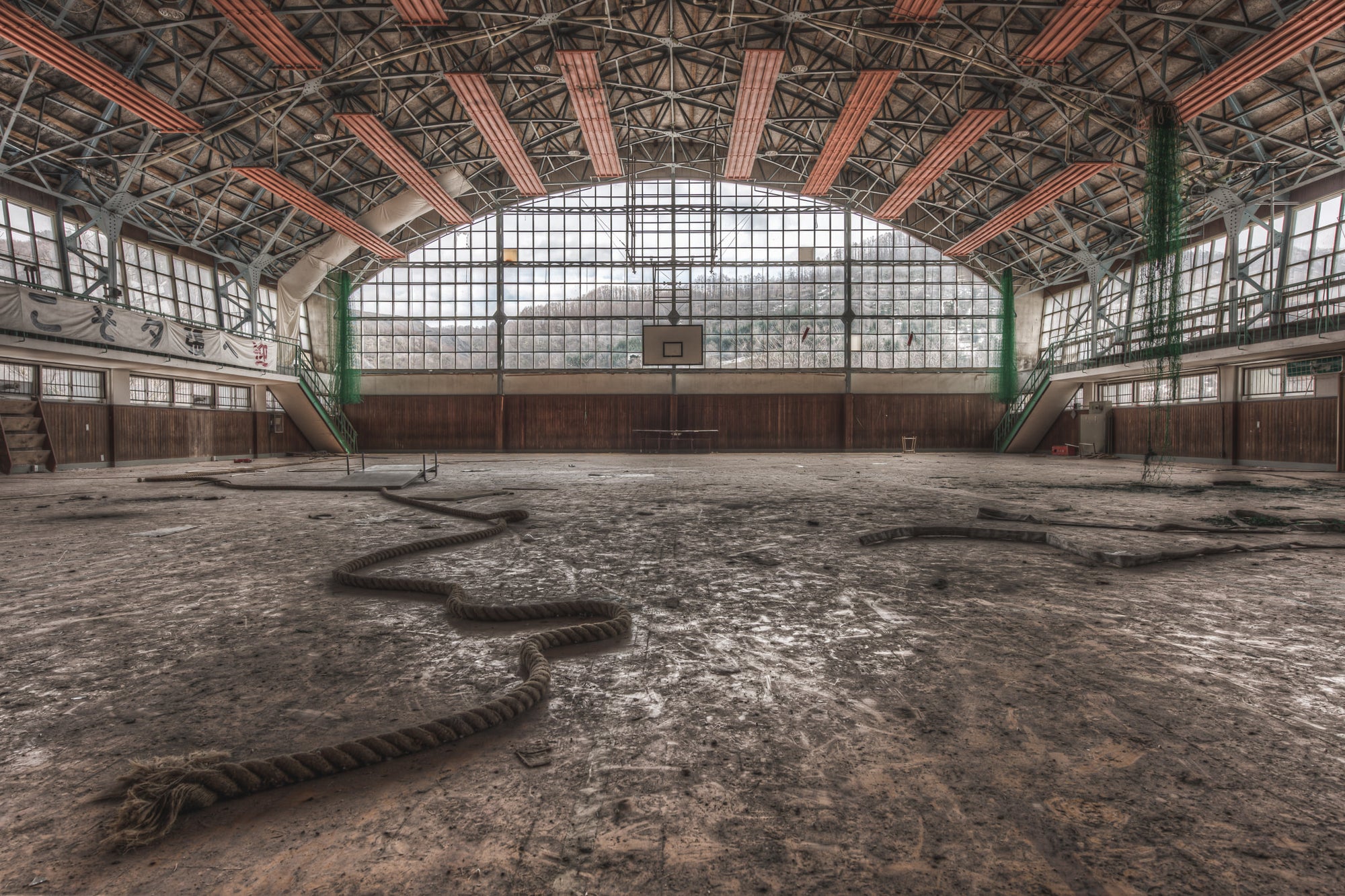 Gymnasium at Family School Fureai, a thick climbing rope lies coiled across the gymnasium floor like something shed.