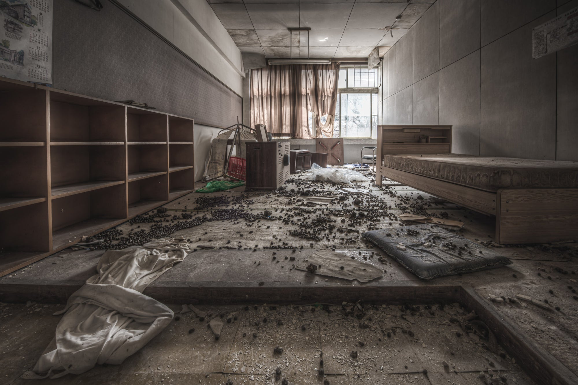 Sick Room at Family School Fureai, a bed frame sits against the far wall, its mattress pulled to the floor and covered.