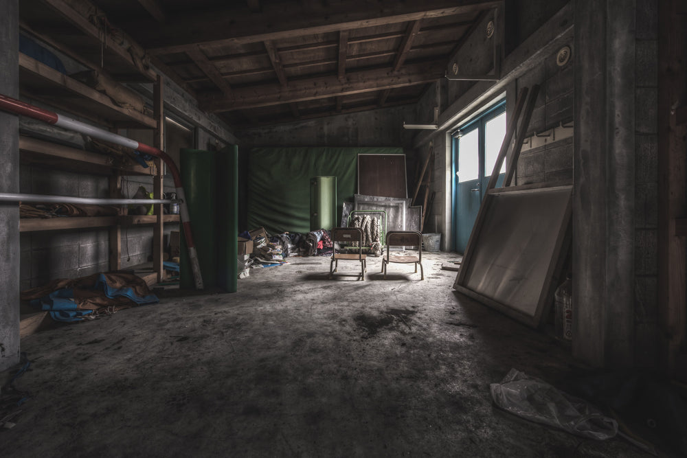 Sports Storage at Family School Fureai, a dim concrete-floored storage room stretches back toward a single window.