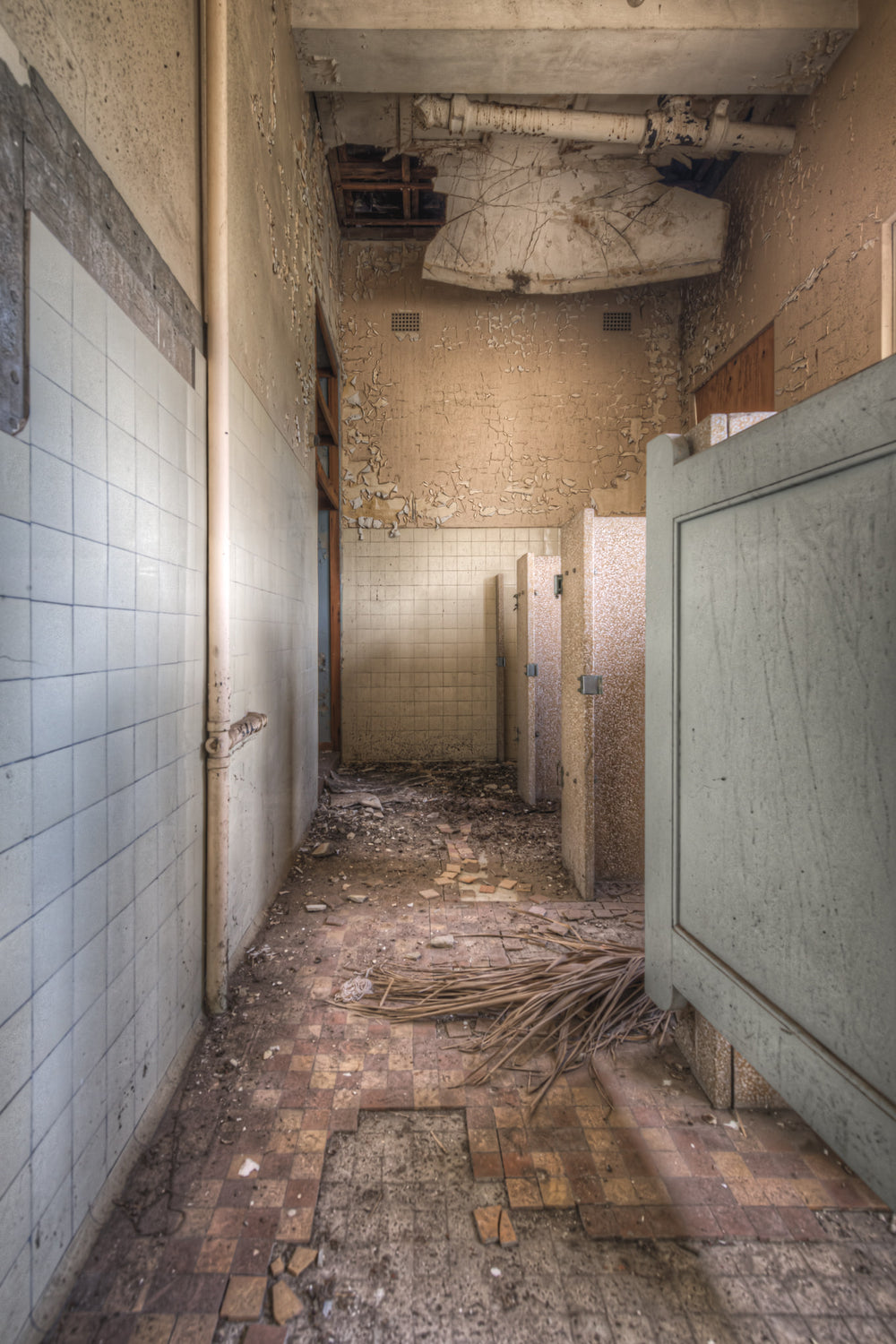 Bathroom Wall at Female Ward 9 & 10, white ceramic tiles line the left wall, cracked and pulling away from the substrate.