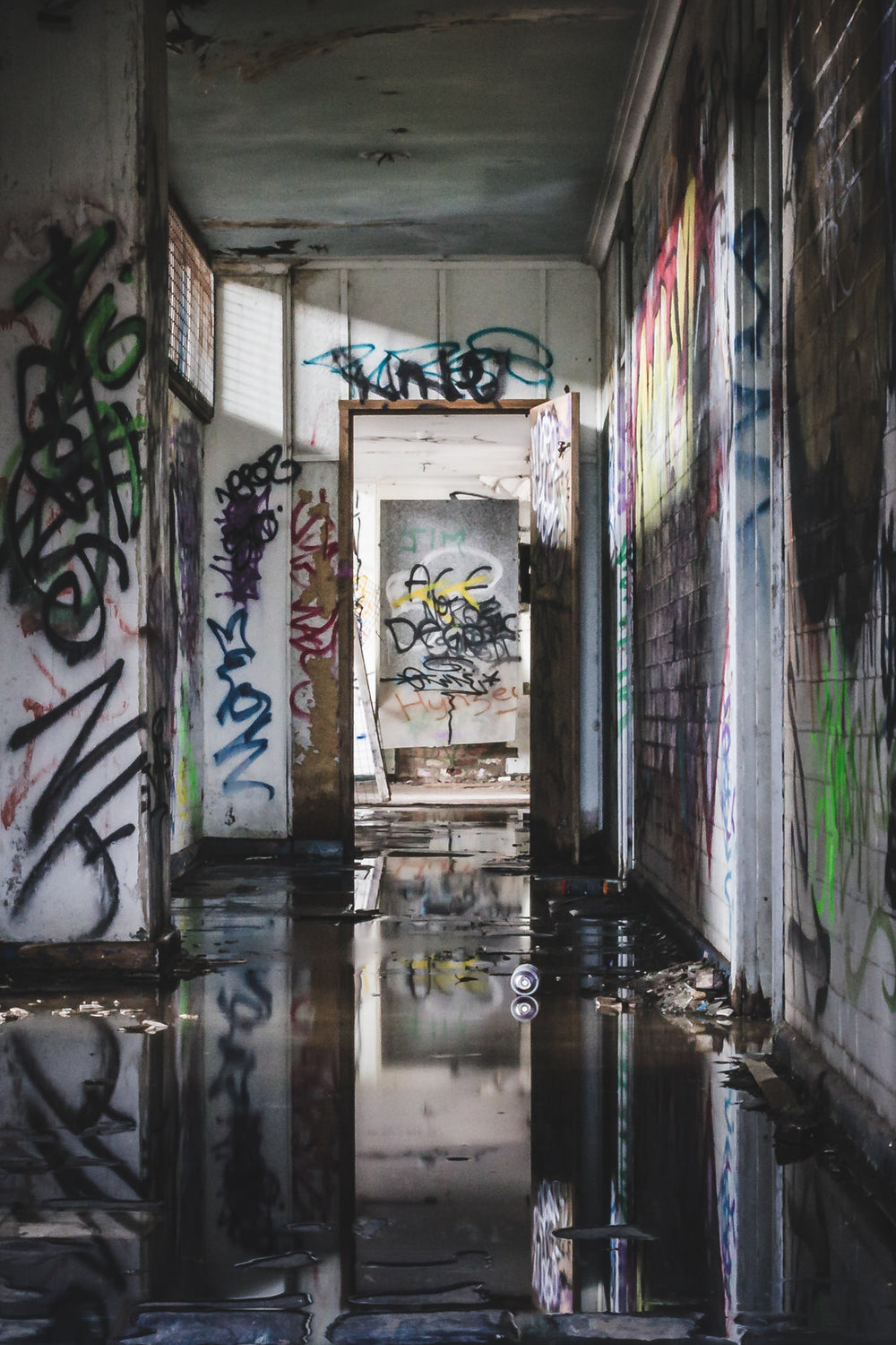 Reflections at Geelong B Power Station, standing water covers the corridor floor, black and still enough to mirror.