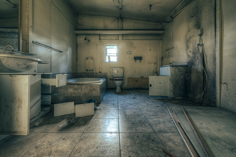 Bathroom at Halvorsens Boat Yard, cabinet doors hang open, drawers pulled from their runners and left on the floor.